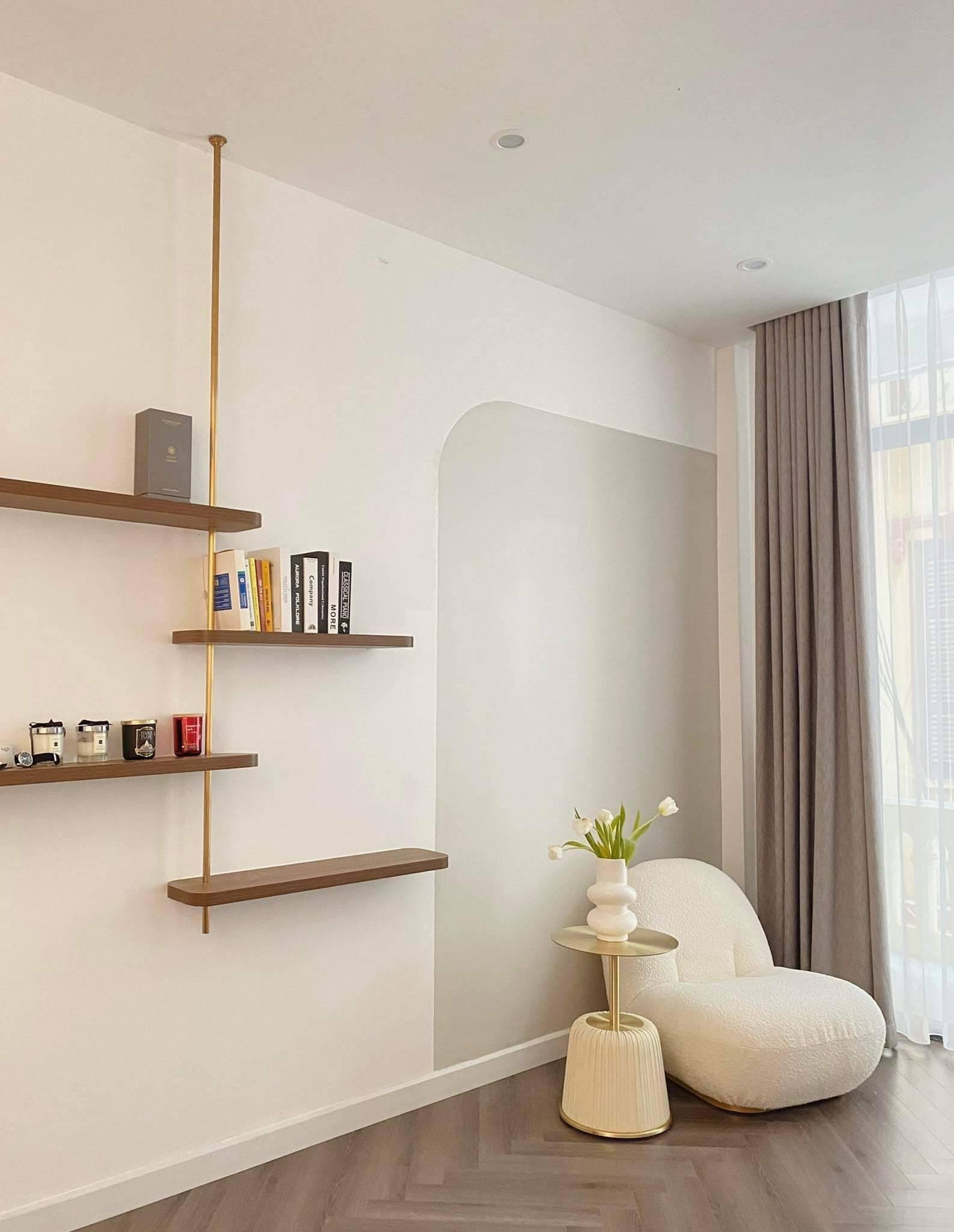 Phòng khách được sơn lại, phần cửa gỗ và cửa sổ được phá bỏ để làm thành ban công - nơi cung cấp nguồn sáng chính cho ngôi nhà. Trong phòng khách, gia chủ bỏ hết các đồ nội thất cũ như tivi, tủ gỗ, bàn gỗ, thay vào đó là kệ để sách sát tường xinh xắn, một ghế sofa trắng bên cạnh bình hoa, sàn lát gỗ để tạo điểm nhấn cho không gian.