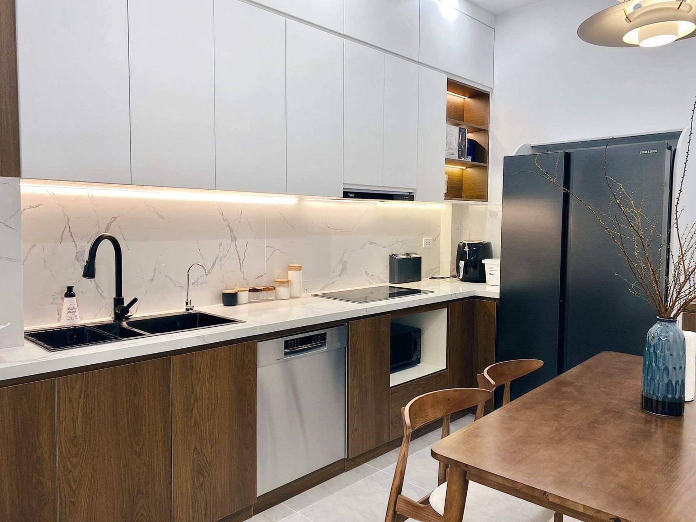 Phần bếp được lược bỏ phần sàn, tường được sơn trắng, hệ thống tủ bếp cũ được thay thế bằng tủ bếp hiện đại, tiện nghi.