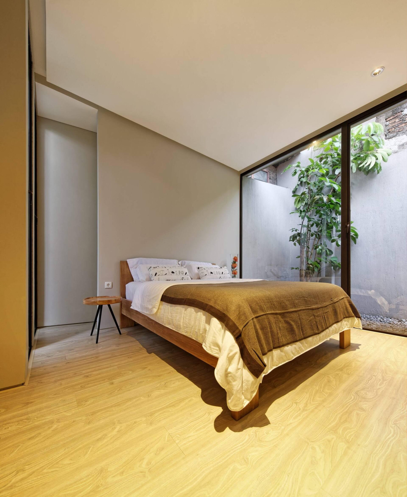 Phòng ngủ được bố trí ở vị trí kín đáo hơn, tăng tính riêng tư và ấm cúng, có tầm nhìn ra khoảng sân nhỏ với nhiều cây cối xanh mướt.