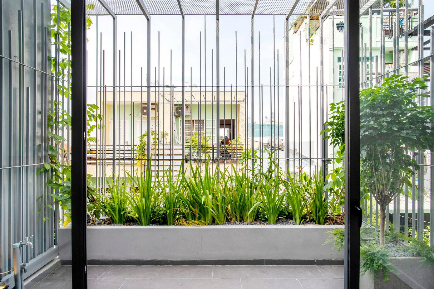 Hai sân thượng lớn với nhiều cây lá và hoa sống động được giấu một phần ngay sau mặt tiền bằng kim loại.