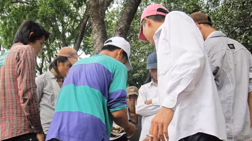 Con bạc chen chúc quanh một sới bạc và chăm chú nhìn vào bàn quay chờ đợi vận may. Ảnh chụp tại công viên Gia Định. Ảnh: Ngọc Khải (Tuổi Trẻ)