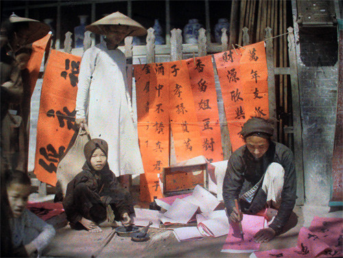  Ông đồ vận áo the nâu, quần trắng, khăn thếp có học trò mài mực giúp