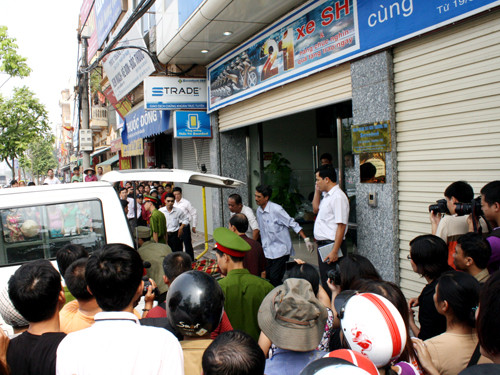 Xác nạn nhân được xe cứu thương đưa ra khỏi ngân hàng, rất đông ngườ dân và phóng viên tới theo dõi vụ việc