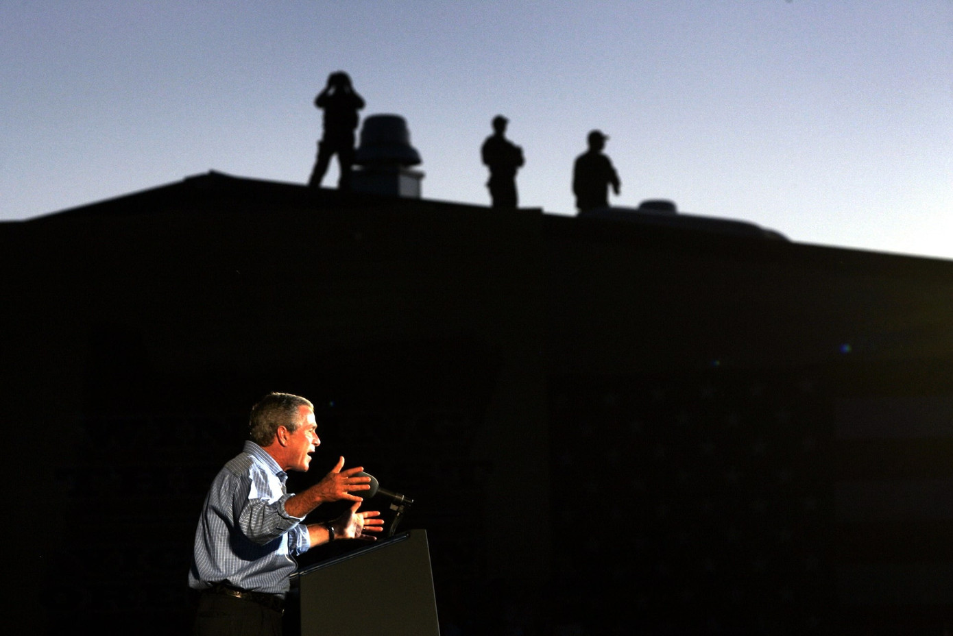 Tổng thống George W. Bush nói chuyện với những người ủng hộ ở Central Point (bang Oregon) ngày 14/10/2004. Các đặc vụ đứng trên nóc mái nhà gần đó. (Ảnh: Reuters)