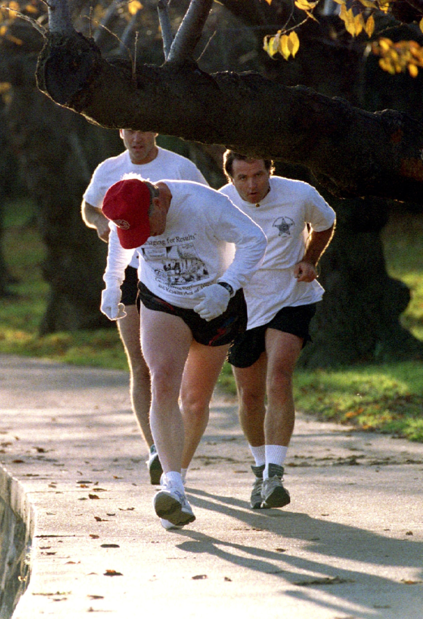 Tổng thống Bill Clinton cúi đầu để tránh cành cây anh đào khi ông chạy bộ cùng các đặc vụ trên con đường quanh Tidal Basin ở Washington ngày 16/11/1993. (Ảnh: Reuters)