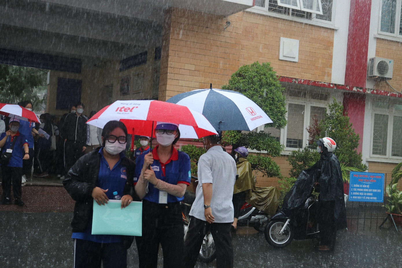 Hình ảnh tình nguyện viên che dù cho thí sinh tránh mưa Hình ảnh tình nguyện viên che dù cho thí sinh tránh mưa