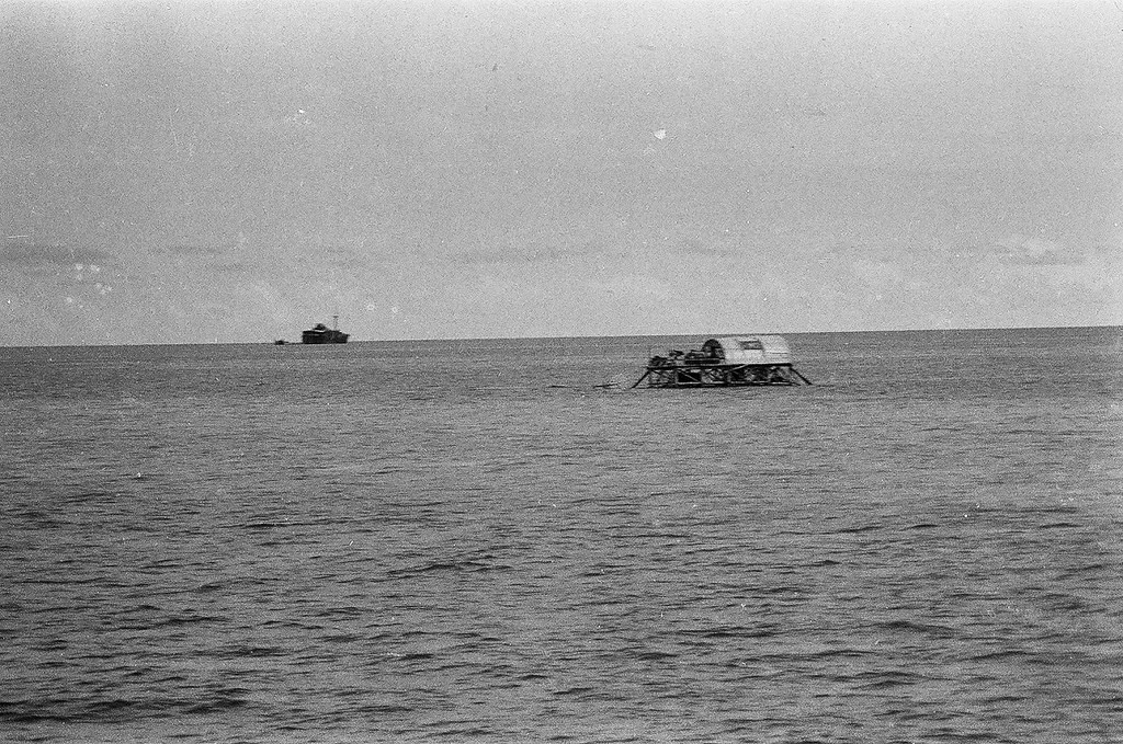 Nhà cao cẳng trên đảo Đá Lát. Cờ Tổ quốc được sơn lên mái tôn như khẳng định chủ quyền của Việt Nam trên đảo này. Xa xa là những gì còn lại của chiếc tàu Tuscany bị bão đánh dạt lên đảo từ năm 1962