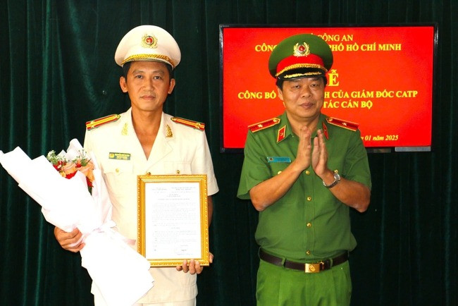 Thiếu tướng Nguyễn Thanh Hưởng, Phó Giám đốc Công an TP HCM, trao quyết định bổ nhiệm và tặng hoa chúc mừng Trung tá Nguyễn Chí Thành. Ảnh: NLĐ.