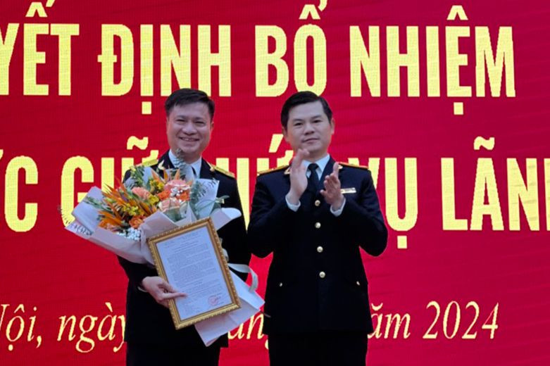 Ông Vũ Chí Hùng - Phó Tổng cục trưởng Tổng cục Thuế trao quyết định và tặng hoa ông Nguyễn Tiến Minh - Phó Cục trưởng Thuế Hà Nội. (Ảnh NT).