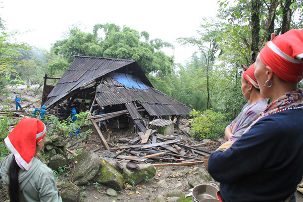 Bà con dân bản chứng kiến lực lượng chức năng dọn dẹp một ngôi nhà bị đổ