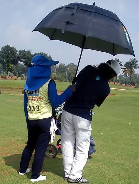 Caddy lúc nào cũng phải đi cùng khách chơi golf để phục vụ mọi yêu cầu từ che dù, đưa gậy, đưa nước.... Ảnh: Vũ Thủy