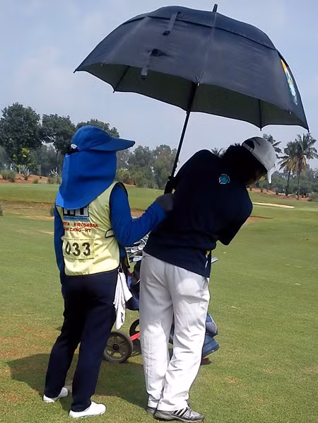 Caddy lúc nào cũng phải đi cùng khách chơi golf để phục vụ mọi yêu cầu từ che dù, đưa gậy, đưa nước.... Ảnh: Vũ Thủy
