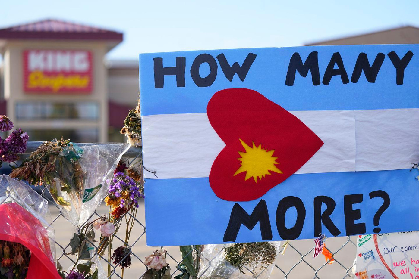 Một địa điểm tưởng niệm các nạn nhân của một vụ xả súng ở Mỹ. Tấm biển có hình đạn bắn vào tìm có dòng chữ “Bao nhiêu người nữa?”. Ảnh: Boston Globe.