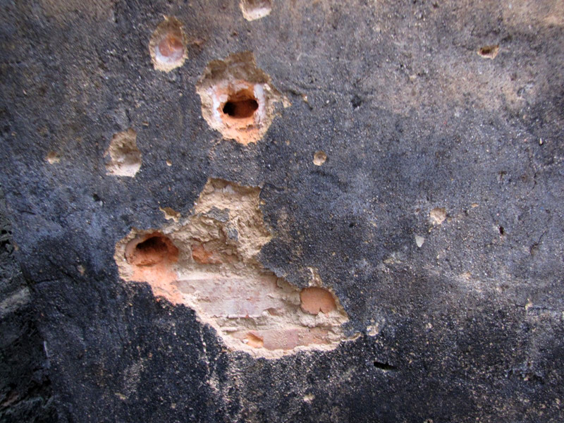 Chiếc xe máy phát nổ, bắn tung tóe vào hai bờ tường bênh cạnh đường đi, khiến tường thủng lỗ chỗ. Ảnh: Tuấn Nguyễn