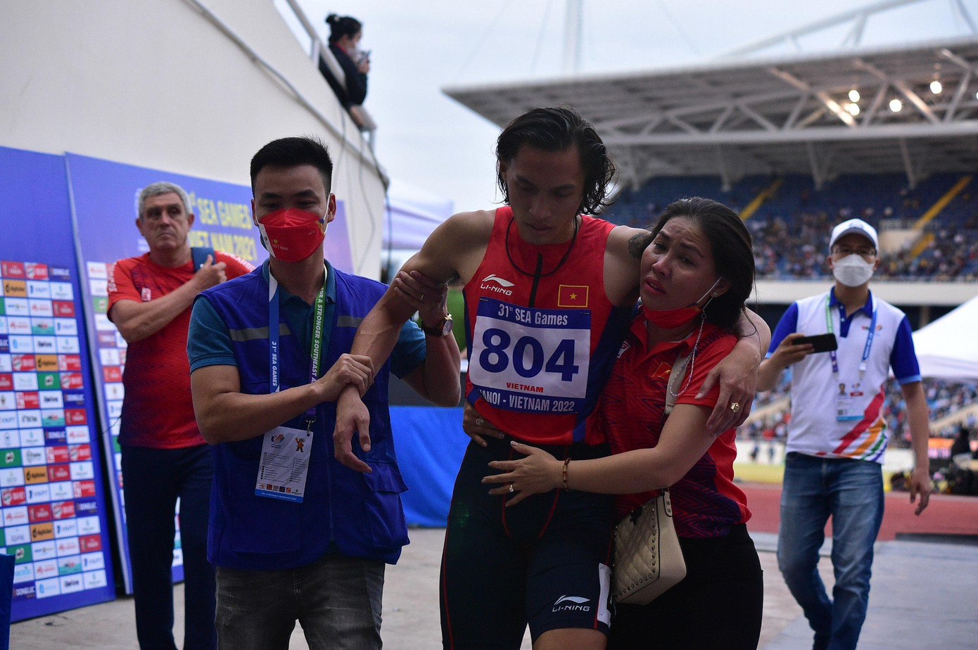 Anh gặp chấn thương và được mẹ dìu ra sân.