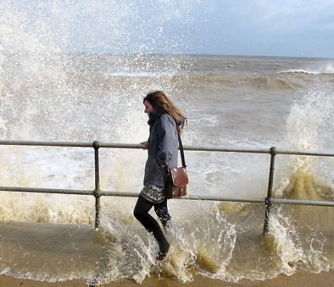 Trong khi nhiều gia đình tại Walcott, bắc Norfolk rời nhà cửa để tạm lánh vì sóng dữ thì cô gái này hào hứng đùa nghịch với con sóng. Ảnh: Rex.