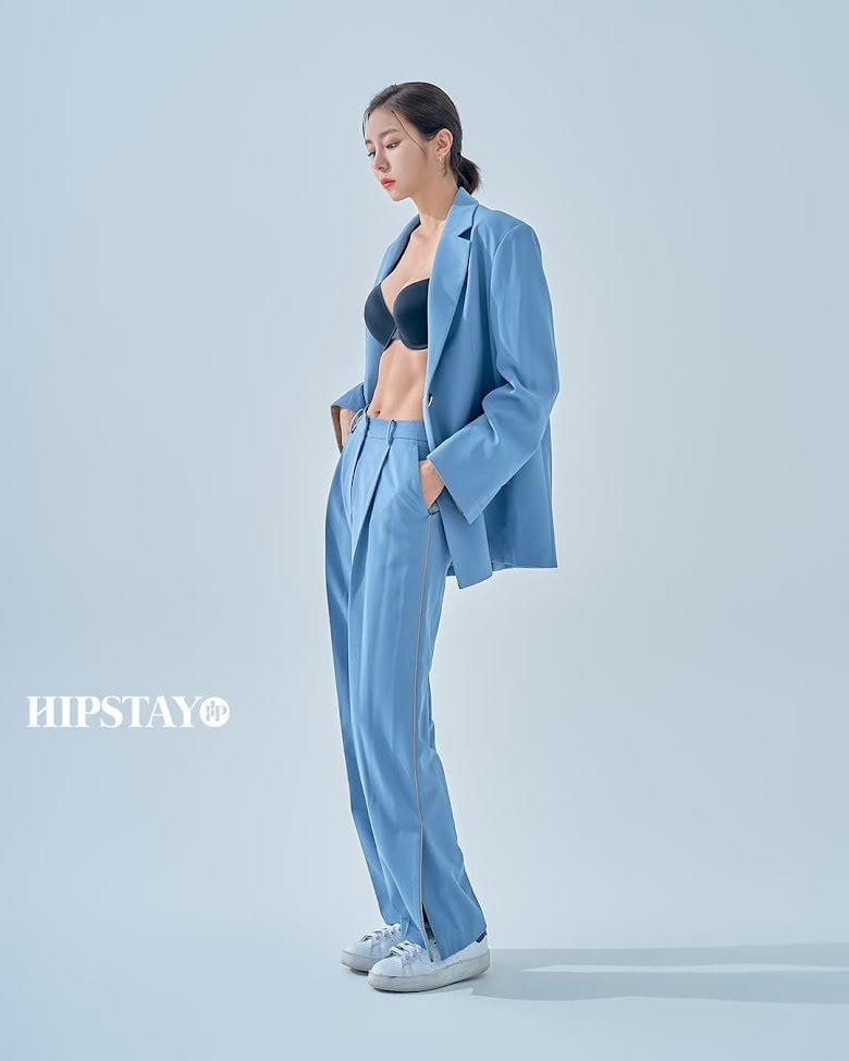 Ở shoot hình khác, người đẹp 33 tuổi mặc bộ vest màu xanh phối với giày thể thao trắng. Cô tự tin phanh áo lộ nội y, khoe vòng hai săn chắc nổi rõ cơ.