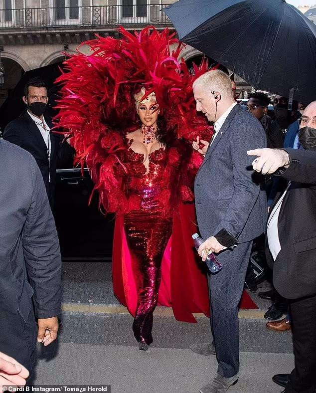 Nữ rapper sinh năm 1992 biến sự kiện thành sàn diễn thời trang của riêng mình khi xuất hiện trong bộ váy đỏ đính sequin lấp lánh, kết hợp áo choàng lông vũ ấn tượng. Cô đeo trang sức và kẻ lông mày "ton-sur-ton". Mái tóc vàng tạo kiểu cổ điển cầu kỳ.