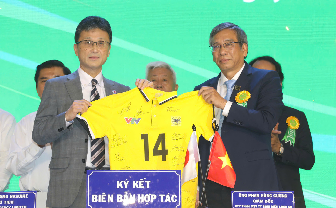 Đại diện CLB VTV Bình Điền Long An (phải) tặng áo đấu cho đại diện CLB PFU Bluecats sau khi ký kết hợp tác.