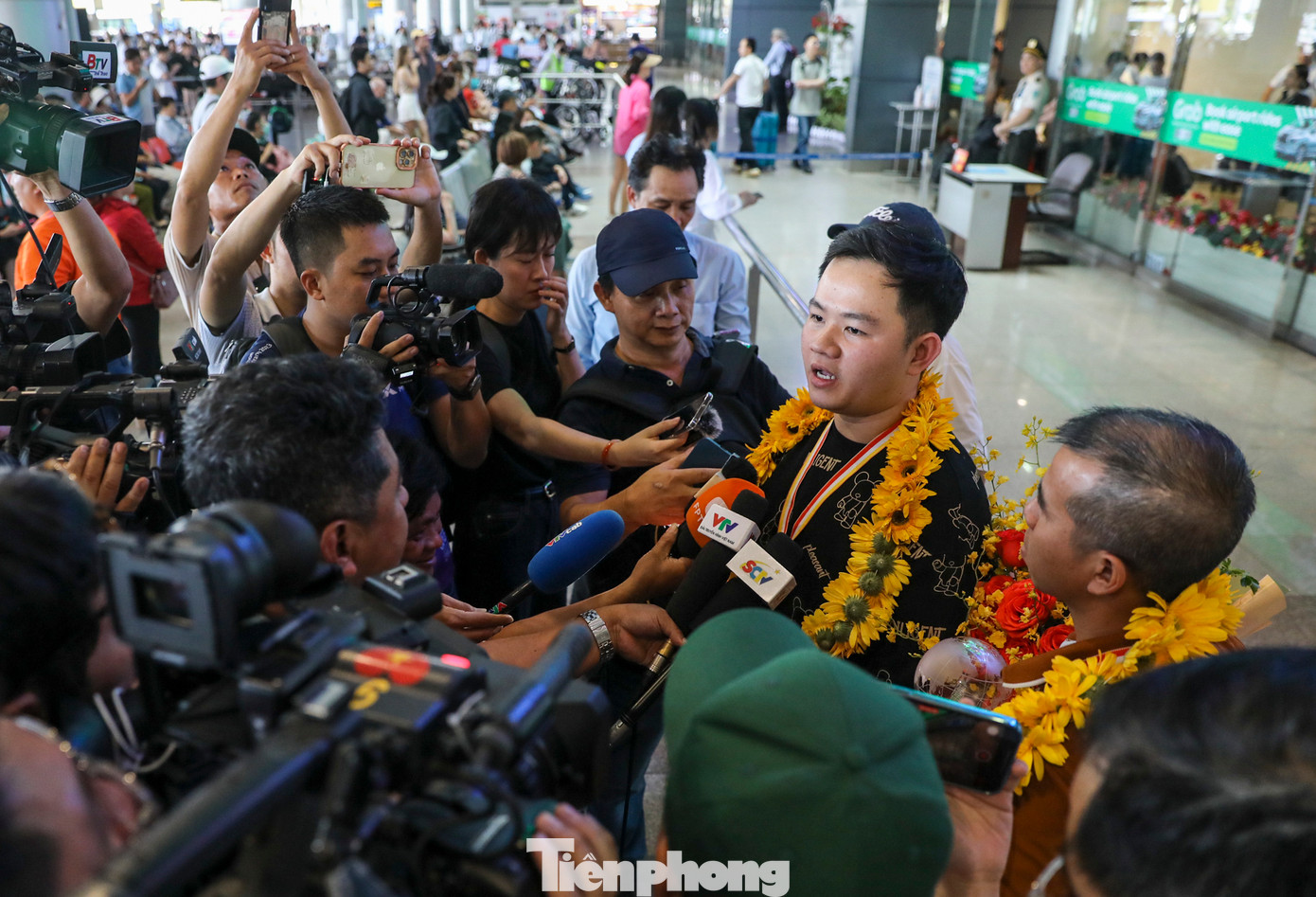 Đông đảo truyền thông và người hâm mộ vây quanh Trần Quyết Chiến và Bao Phương Vinh tại sân bay.