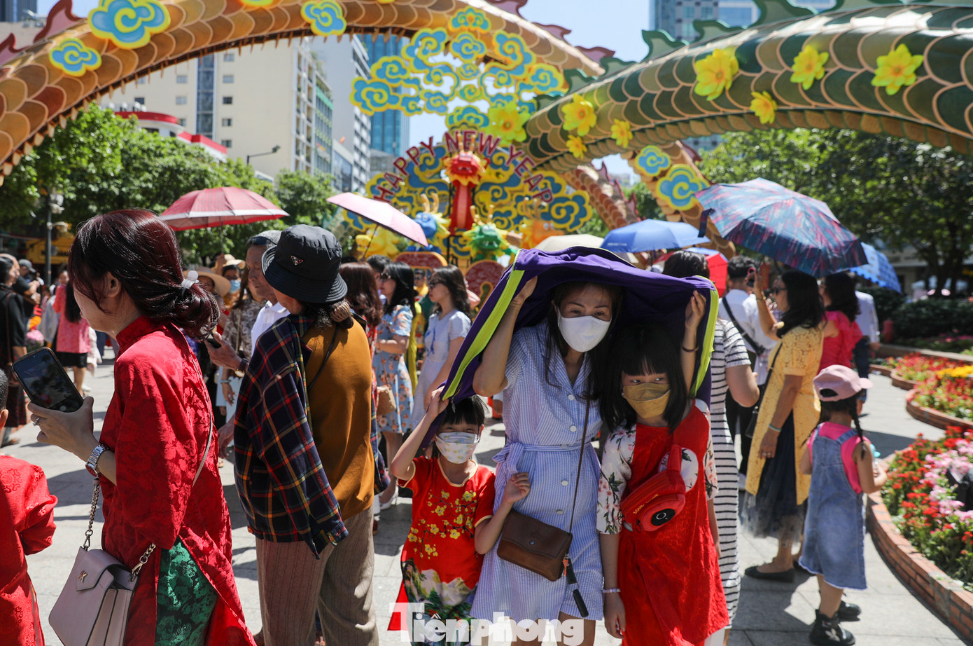 Dưới nền nhiệt ngoài trời lên tới 35 độ C, người dân ở TPHCM đội nhiều lớp mũ, mặc kín mít để du xuân.