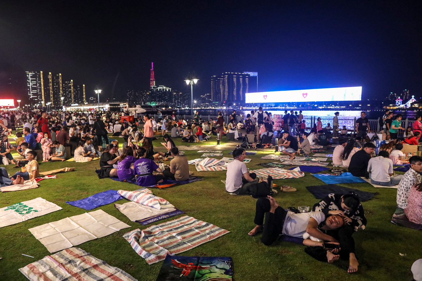 Đến 20h, khuôn viên công viên bến Bạch Đằng gần như bị lấp đầy. Vị trí bờ sông Sài Gòn này khá mát mẻ, nhìn về phía bờ bên kia là khu đô thị mới Thủ Thiêm, TP Thủ Đức được trang trí nhiều hệ thống đèn sáng rực cùng màn hình LED rực rỡ. Đến 20h, khuôn viên công viên bến Bạch Đằng gần như bị lấp đầy. Vị trí bờ sông Sài Gòn này khá mát mẻ, nhìn về phía bờ bên kia là khu đô thị mới Thủ Thiêm, TP Thủ Đức được trang trí nhiều hệ thống đèn sáng rực cùng màn hình LED rực rỡ.