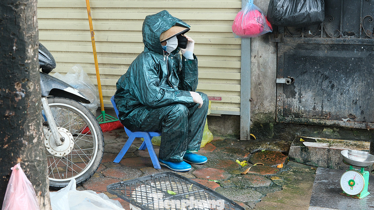 Chị Linh bán hàng cá trên đường Hoàng Cầu co ro trong bộ đồ áo mưa.