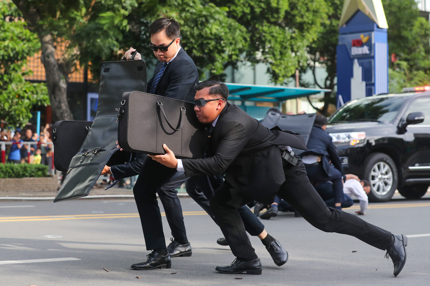 Các cảnh vệ dùng cặp - áo giáp chống đạn, để che chắn, bảo vệ yếu nhân. Trong khi đó, những cảnh vệ khác rút súng bắn liên tiếp nhóm khủng bố.