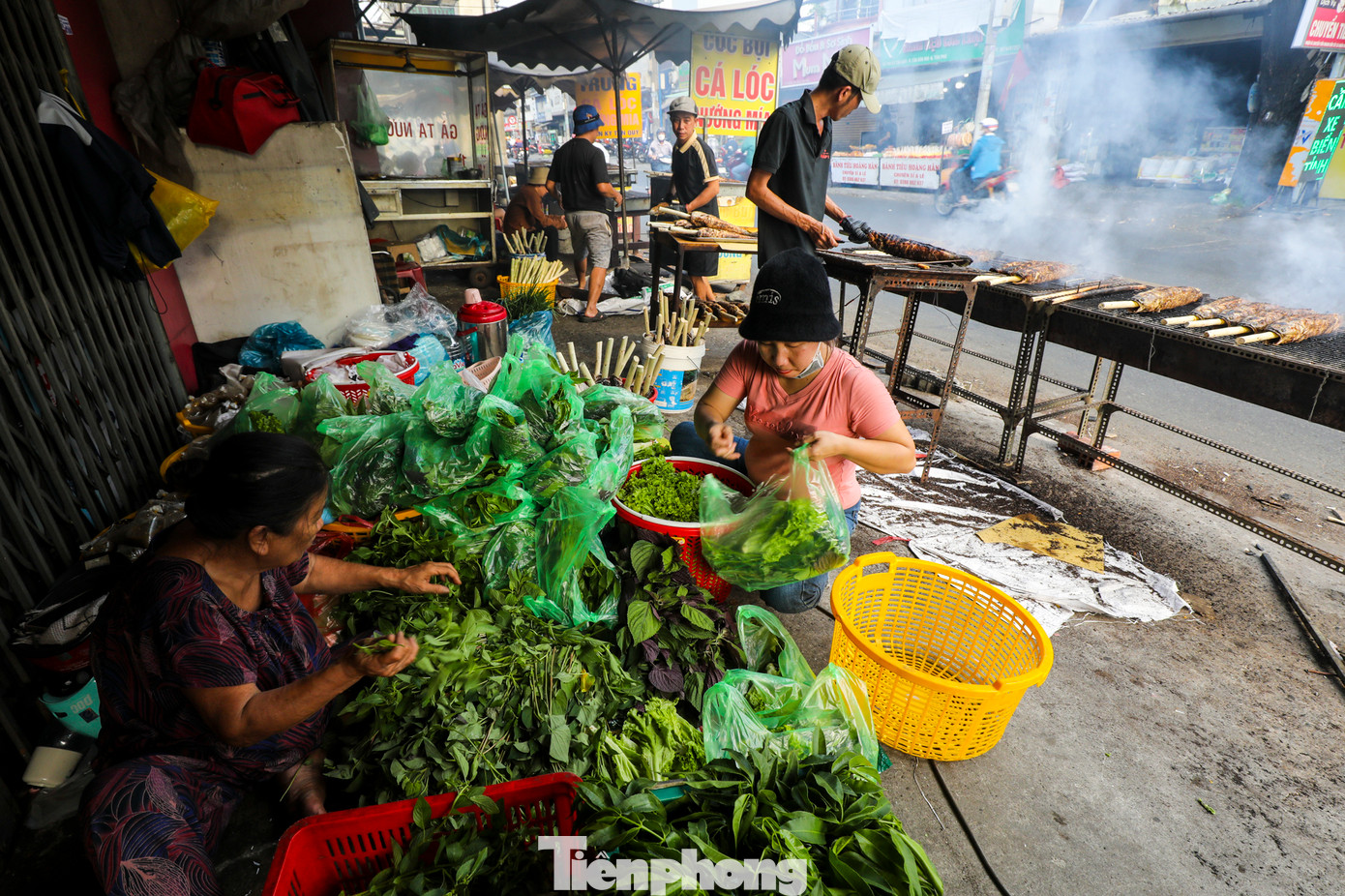 Kề bên khu vực nướng cá, những nhân viên đang tất bật chuẩn bị rau thơm, pha chế mắm nêm, cho bún vào các túi nhỏ để bán kèm với cá lóc nướng. Kề bên khu vực nướng cá, những nhân viên đang tất bật chuẩn bị rau thơm, pha chế mắm nêm, cho bún vào các túi nhỏ để bán kèm với cá lóc nướng.