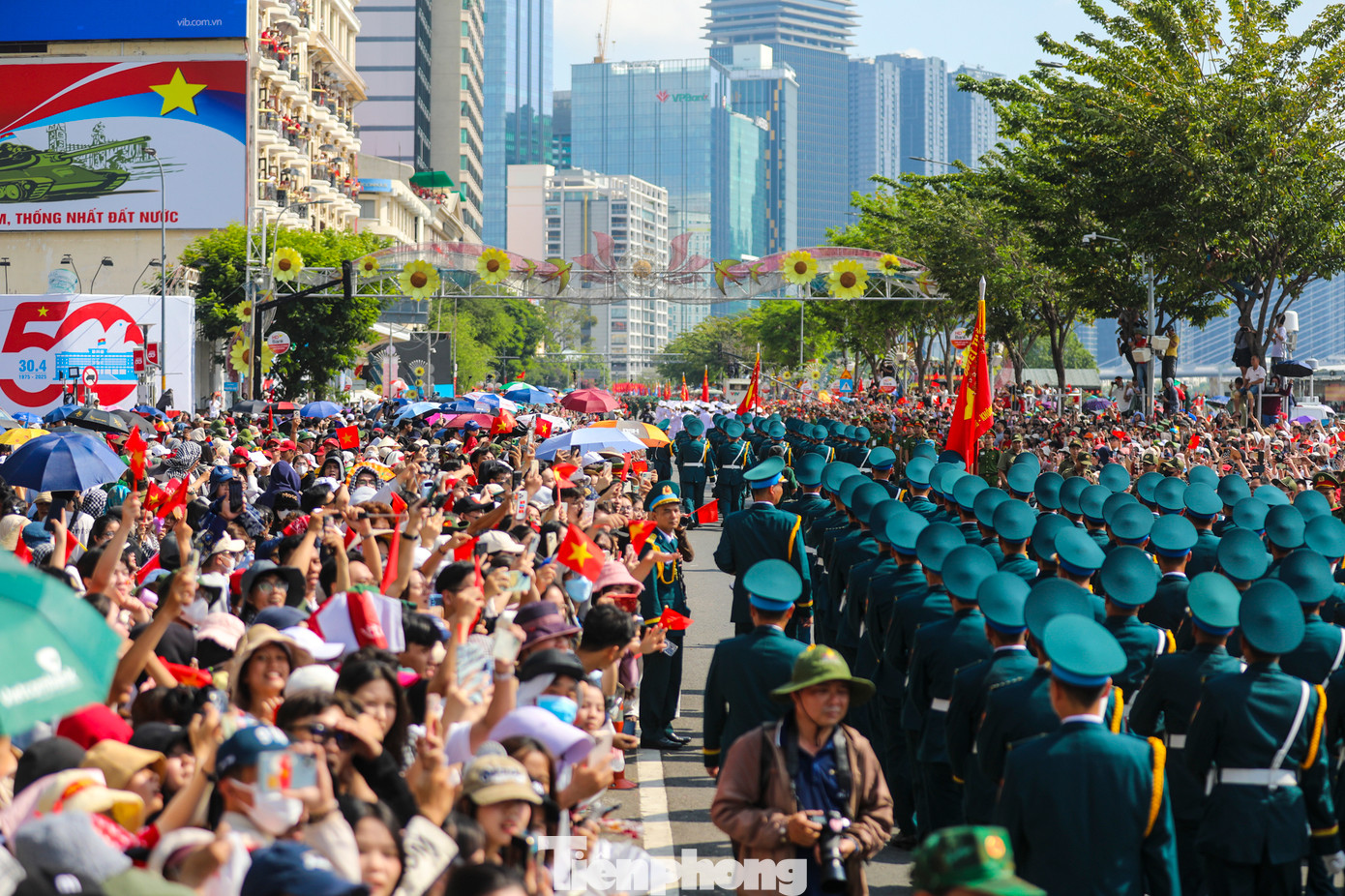 Người dân xếp hàng kín hai bên đường, cùng vẫy cao cờ hoa, hò reo chào đón từng khối diễu binh, diễu hành bước qua.