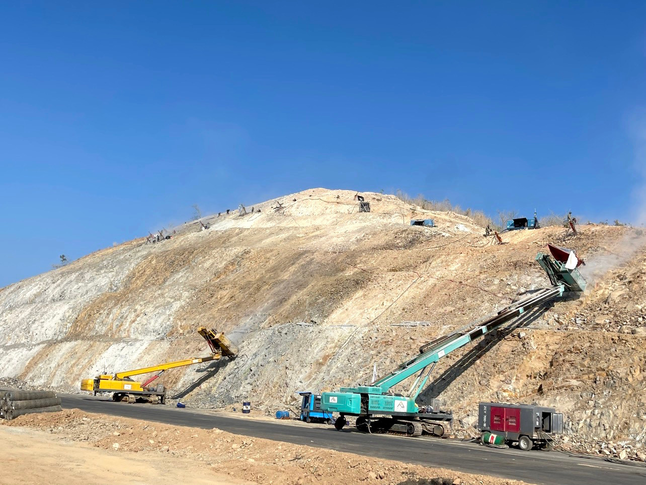 Các loại máy móc, công nhân đang xử lý hai bên taluy đường để chống sạt lở vì bạt núi mở đường. Các loại máy móc, công nhân đang xử lý hai bên taluy đường để chống sạt lở vì bạt núi mở đường.