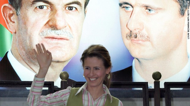 Đệ nhất phu nhân Syria đứng dưới tấm ảnh lớn của tổng thống Assad và cố tổng thống Hafez al-Assad tháng 5/2006