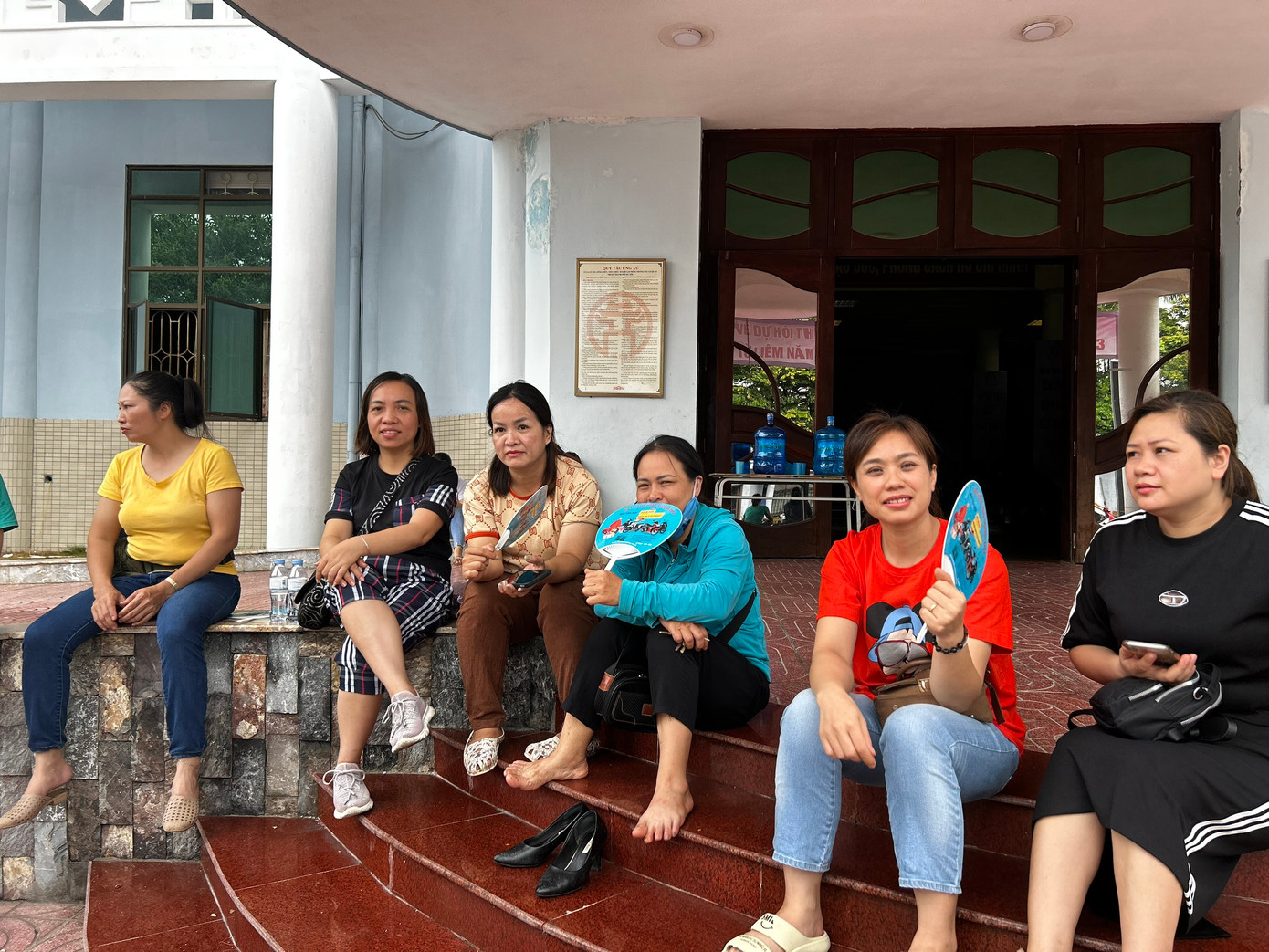 Các phụ huynh trú mưa trong khi đợi con hoàn thành bài thi.