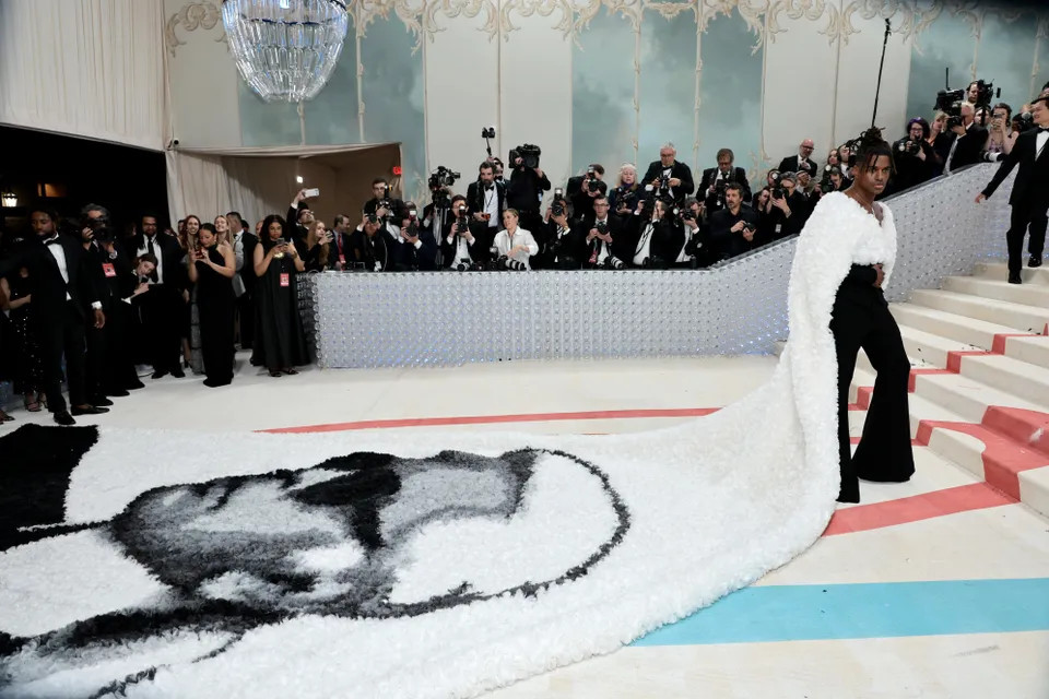 Jeremy Pope bày tỏ lòng tôn kính với nhà thiết kế quá cố qua đuôi áo choàng lông dài hơn 9 mét mang hình ảnh ông. Pope hoàn thiện trang phục cùng quần ống loe đơn giản.