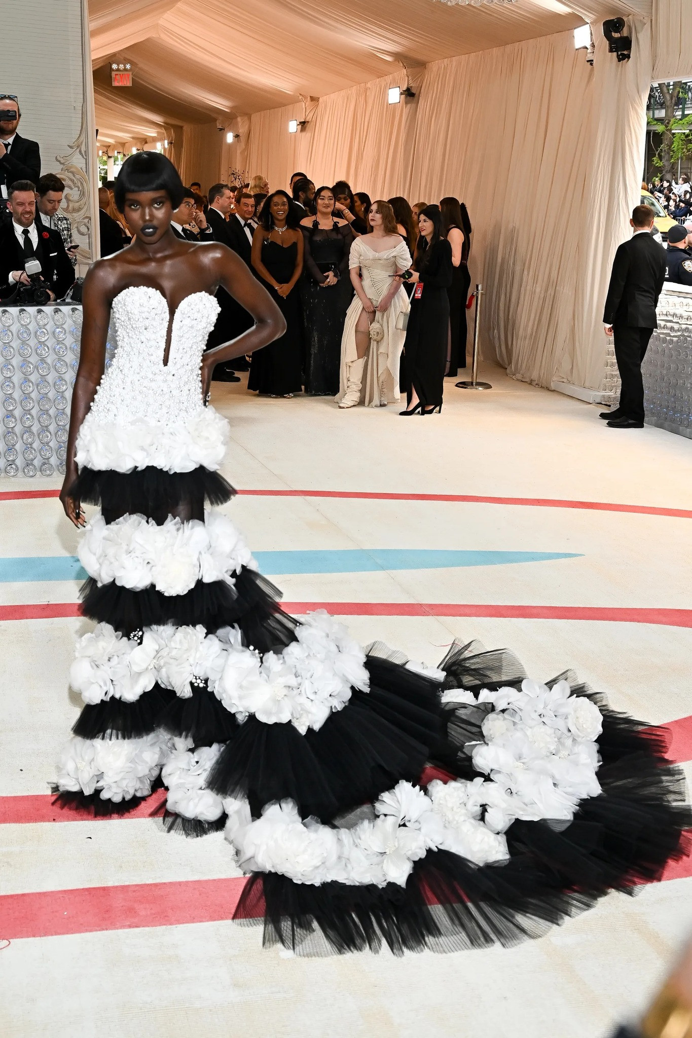 Người mẫu Adut Akech với thiết kế ấn tương, hoa trà đính kết tỉ mỉ trải dài từ eo đổ xuống. Người mẫu Adut Akech với thiết kế ấn tương, hoa trà đính kết tỉ mỉ trải dài từ eo đổ xuống.