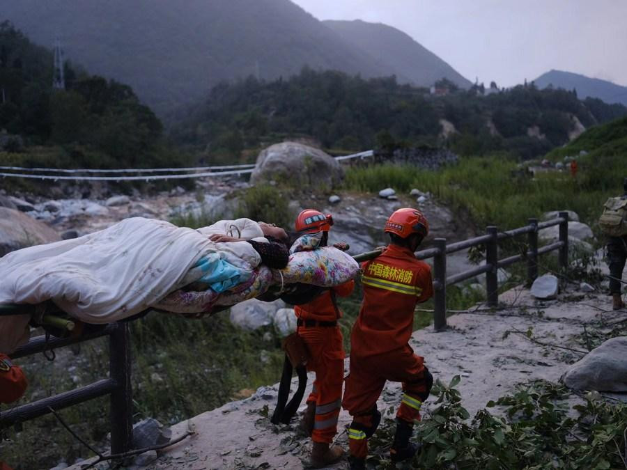 Video từ đài truyền hình nhà nước CCTV cho thấy các nhân viên cứu hộ kéo một người phụ nữ xây xát khắp người ra khỏi đống đổ nát, và vội vàng đưa một người sống sót qua sông bằng một cây cầu tạm. Ảnh: Xinhua