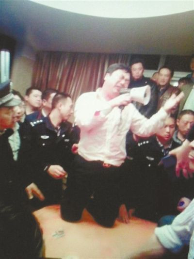 Hình ảnh một quan chức quỳ gối và dùng loa để cầu xin người dân tha tội 