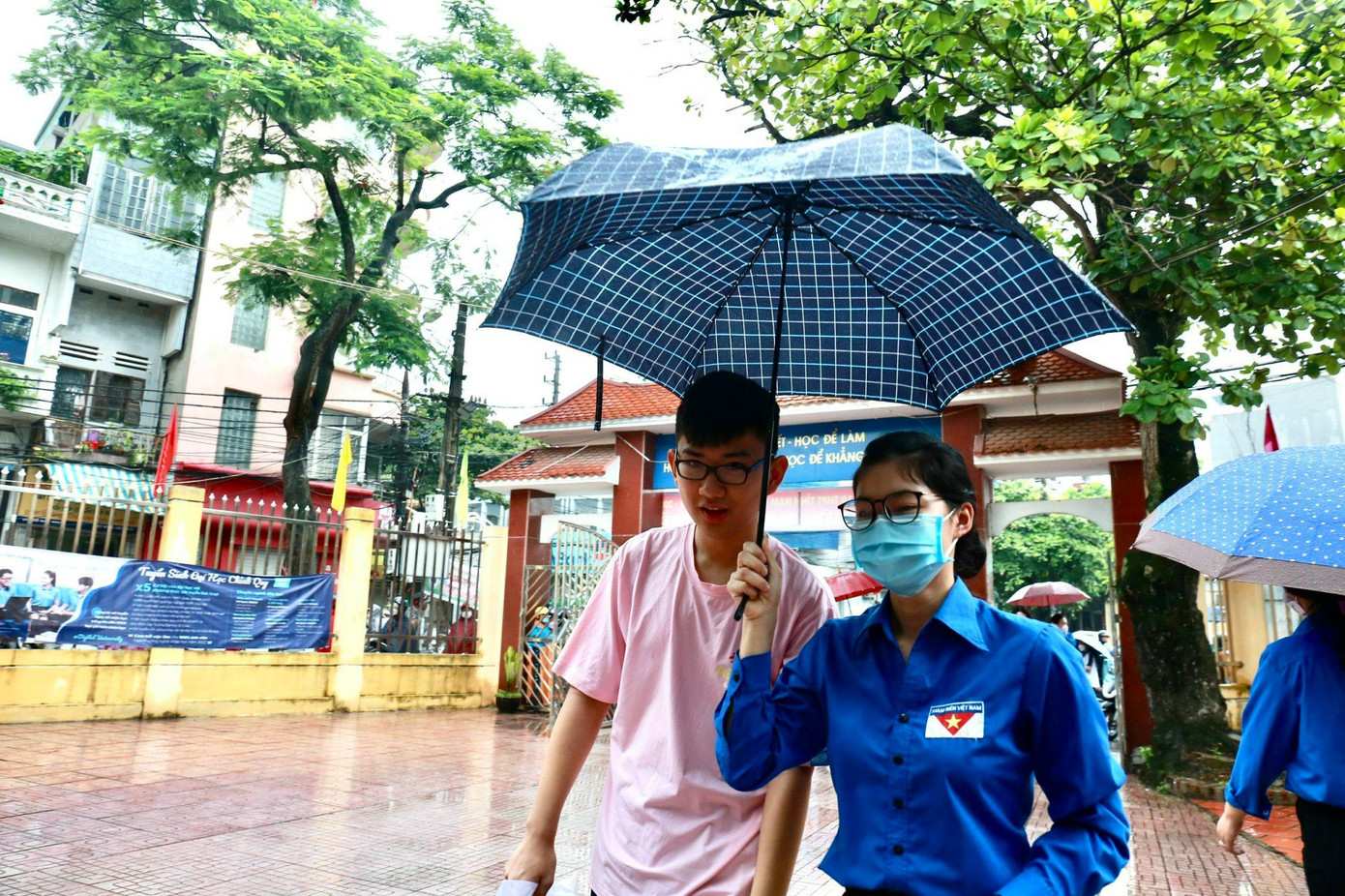 Tình nguyện viên che ô cho thí sinh khỏi ướt mưa đi vào phòng thi Tình nguyện viên che ô cho thí sinh khỏi ướt mưa đi vào phòng thi