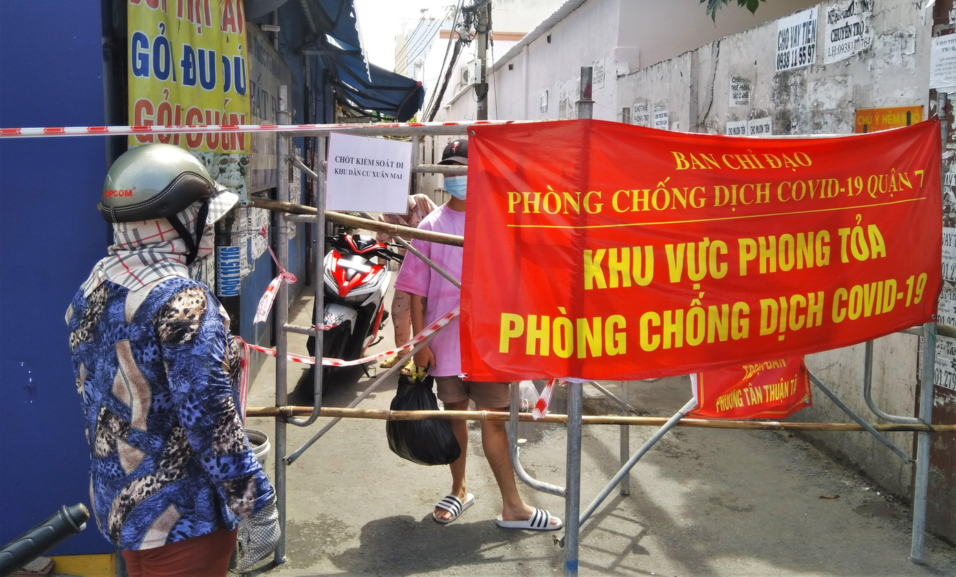 Chị Thắm (trái) đem cơm cho con trai trong khu phong tỏa. Chị nói: "Gia đình tôi ở huyện Nhà Bè, con trai đang làm việc trên này thì bị phong tỏa không về nhà được. Tôi nấu cơm đem lên cho nó ăn vì giờ các điểm bán cơm phở mang về cũng đã ngừng hoạt động. Mong cho dịch bệnh sớm được khống chế để con tôi được về nhà".