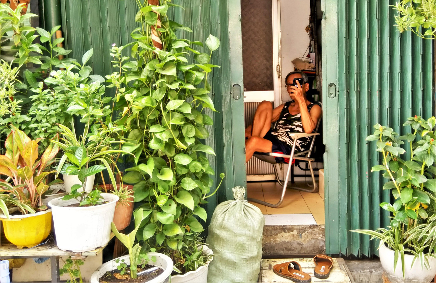 Người đàn ông ở phố Tây Bùi Viện "phong tỏa" nhà bằng cây xanh và ngồi nghe tin tức dịch bệnh COVID-19 qua chiếc điện thoại. Người đàn ông ở phố Tây Bùi Viện "phong tỏa" nhà bằng cây xanh và ngồi nghe tin tức dịch bệnh COVID-19 qua chiếc điện thoại.