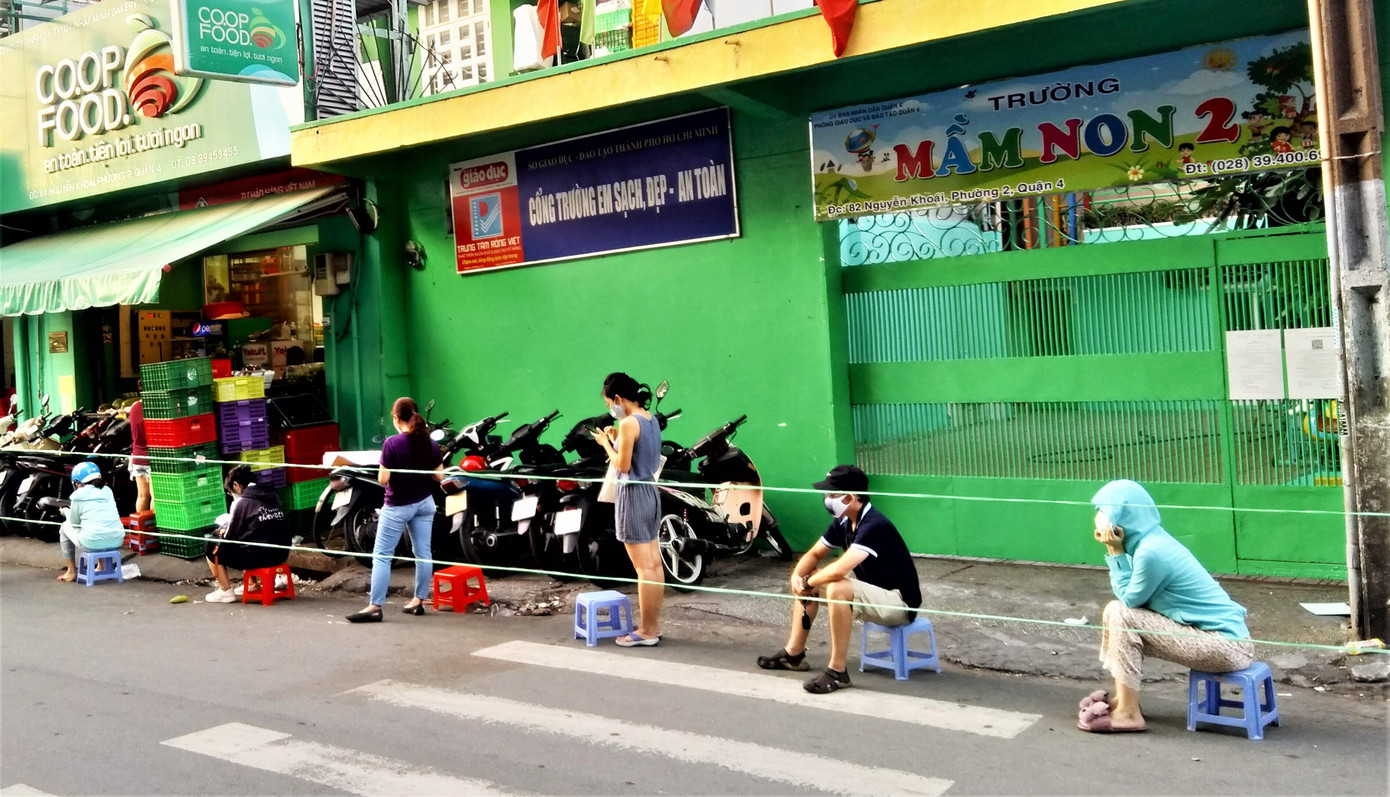 Các cửa hàng tiện lợi trở thành nơi mua sắm trong ngày cách ly xã hội. Trong ảnh là khách hàng ở khu Bến Vân Đồn, quận 4 đang chờ tới lượt của mình bên ngoài cửa hàng tiện lợi.