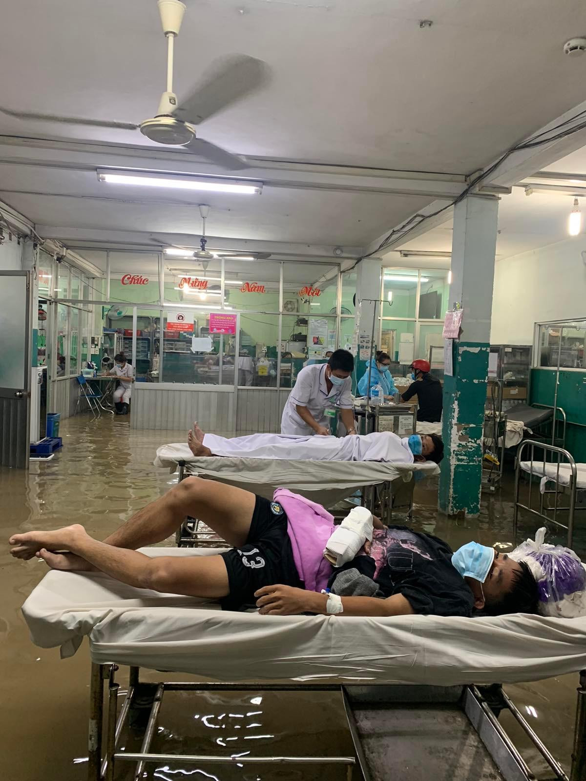 Một bệnh nhân nằm ở khoa cấp cứu bên dưới nước đã dâng cao đến gần gối. Ảnh: Lâm Trần