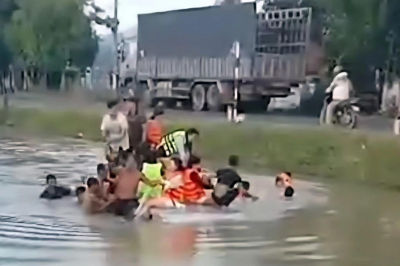 Người dân đưa các nạn nhân trong xe ô tô 16 chỗ lên bờ. Ảnh: Loan Thanh.