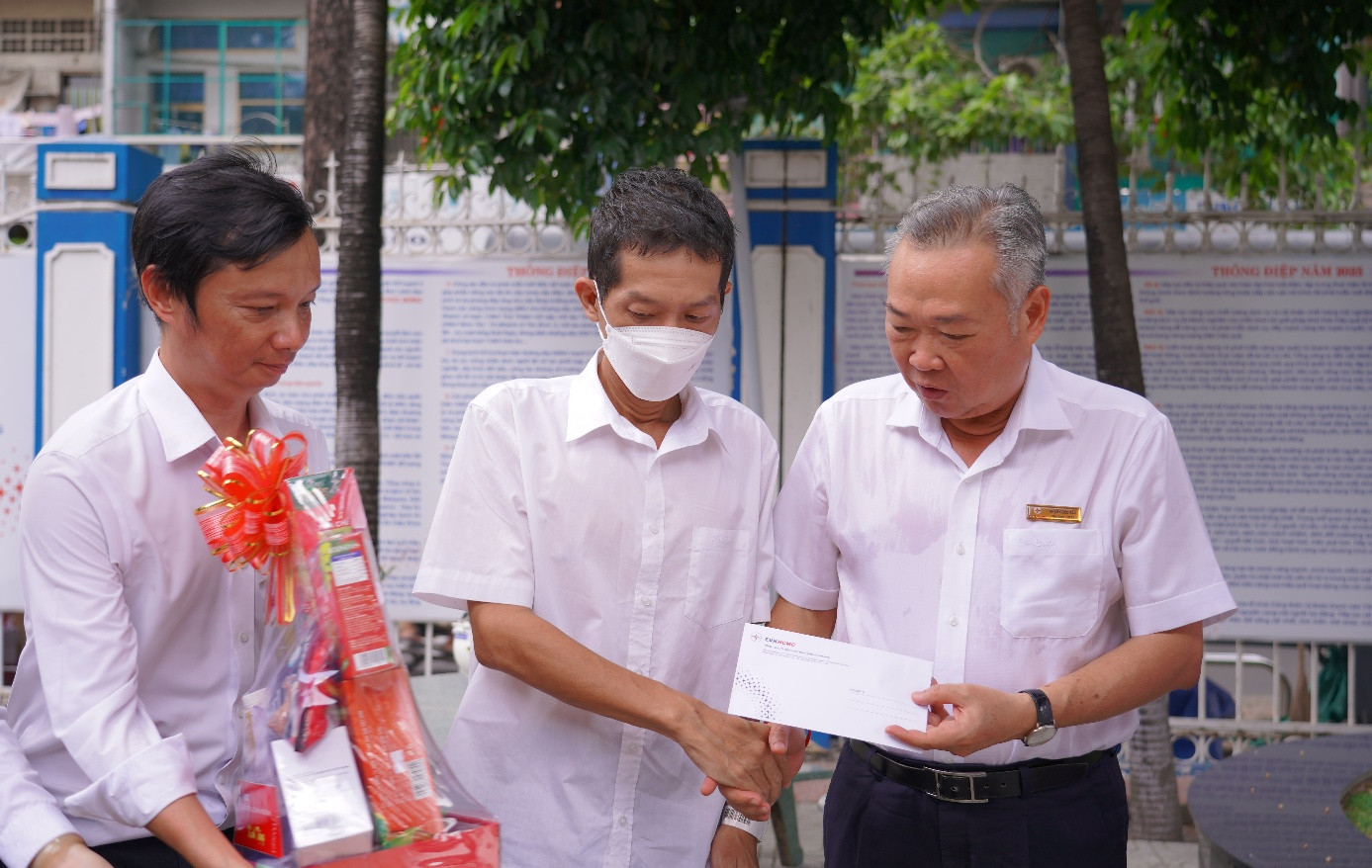 Ông Phạm Quốc Bảo – Chủ tịch HĐTV EVNHCMC (bên phải) tặng quà, động viên anh Đàm Bảo Vy (giữa).