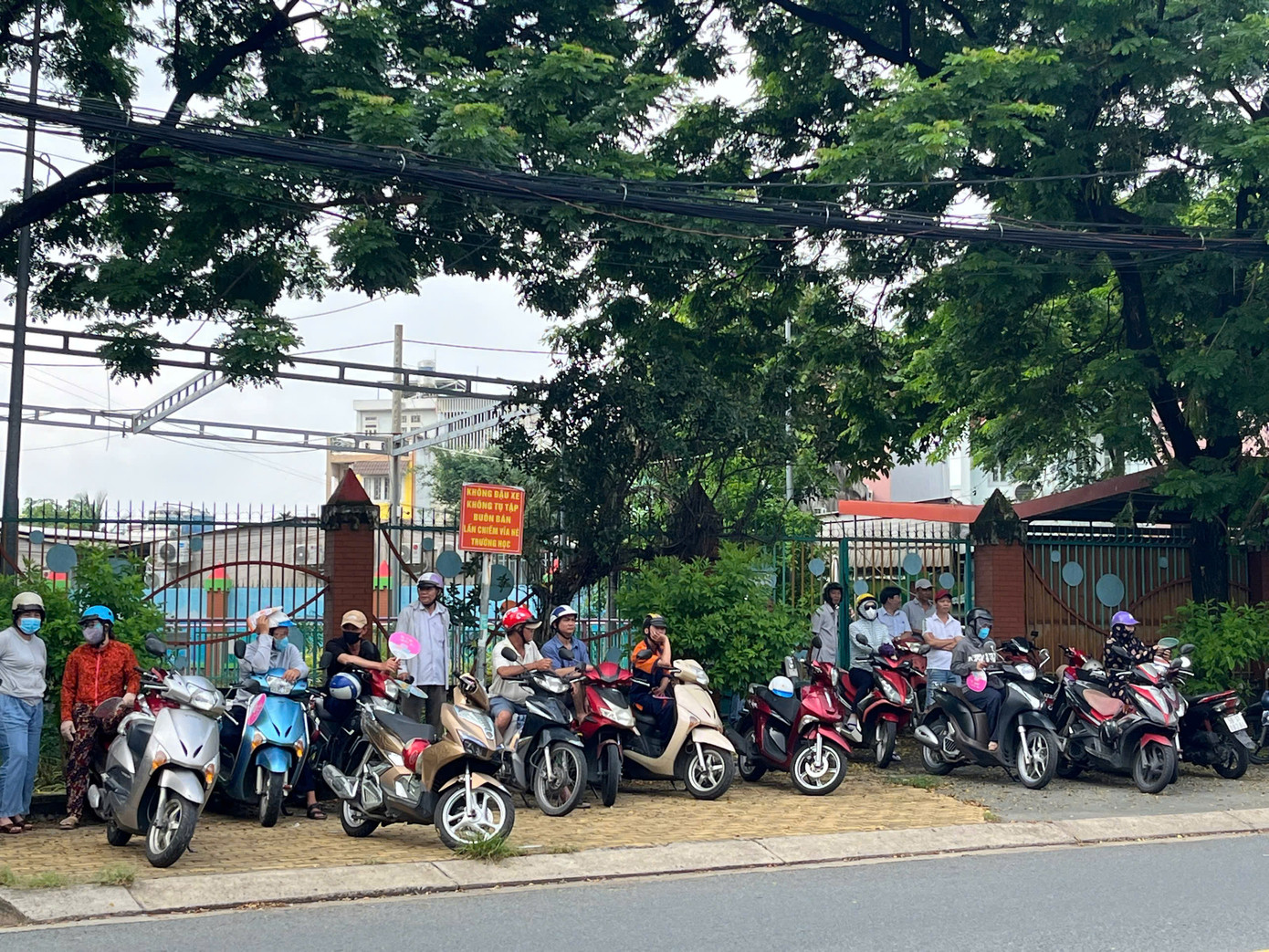 Phụ huynh xếp hàng dài trước cổng trường chờ con mình tan buổi thi trong buổi sáng thi môn tự chọn. Ảnh: Ý Lê