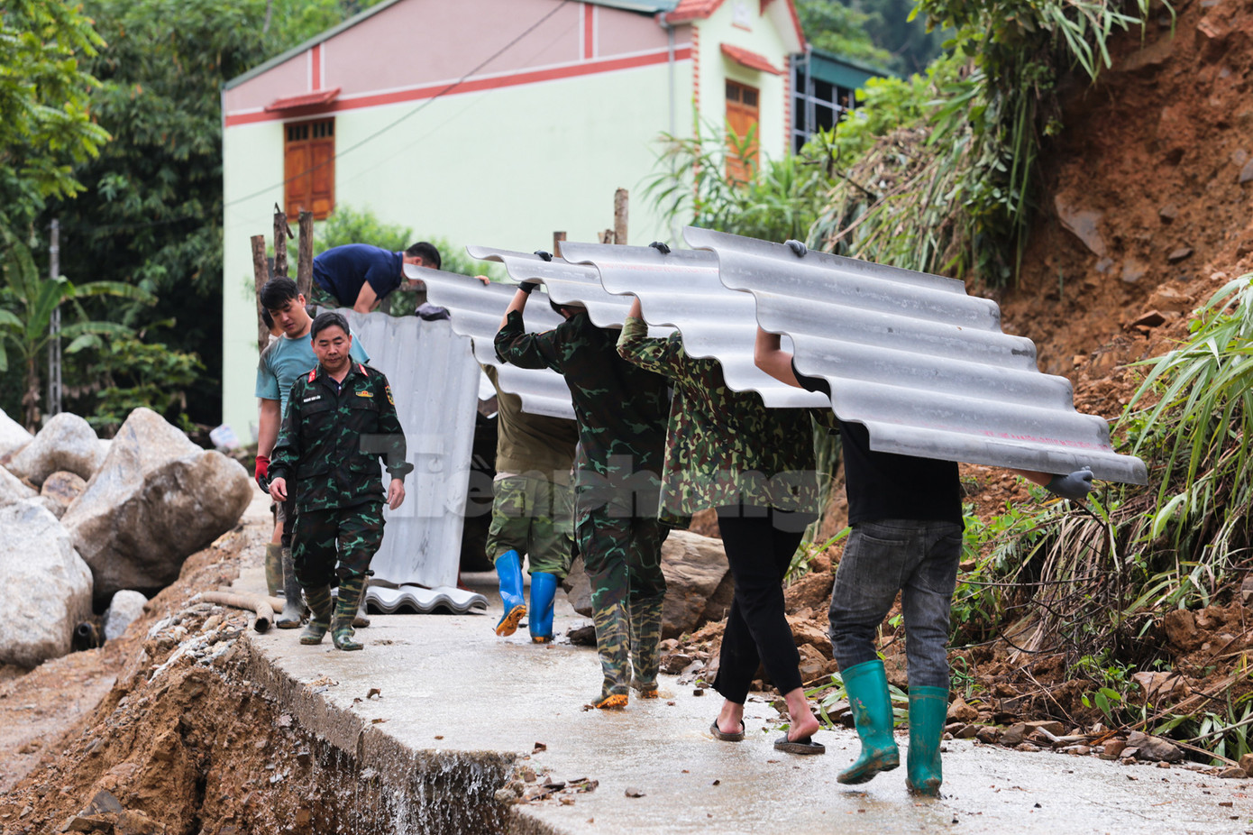 Vật liệu tiếp tục được tập kết và đưa lên xe máy kéo khác chở vào nơi chuẩn bị cất ngôi nhà mới cho gia đình nạn nhân.