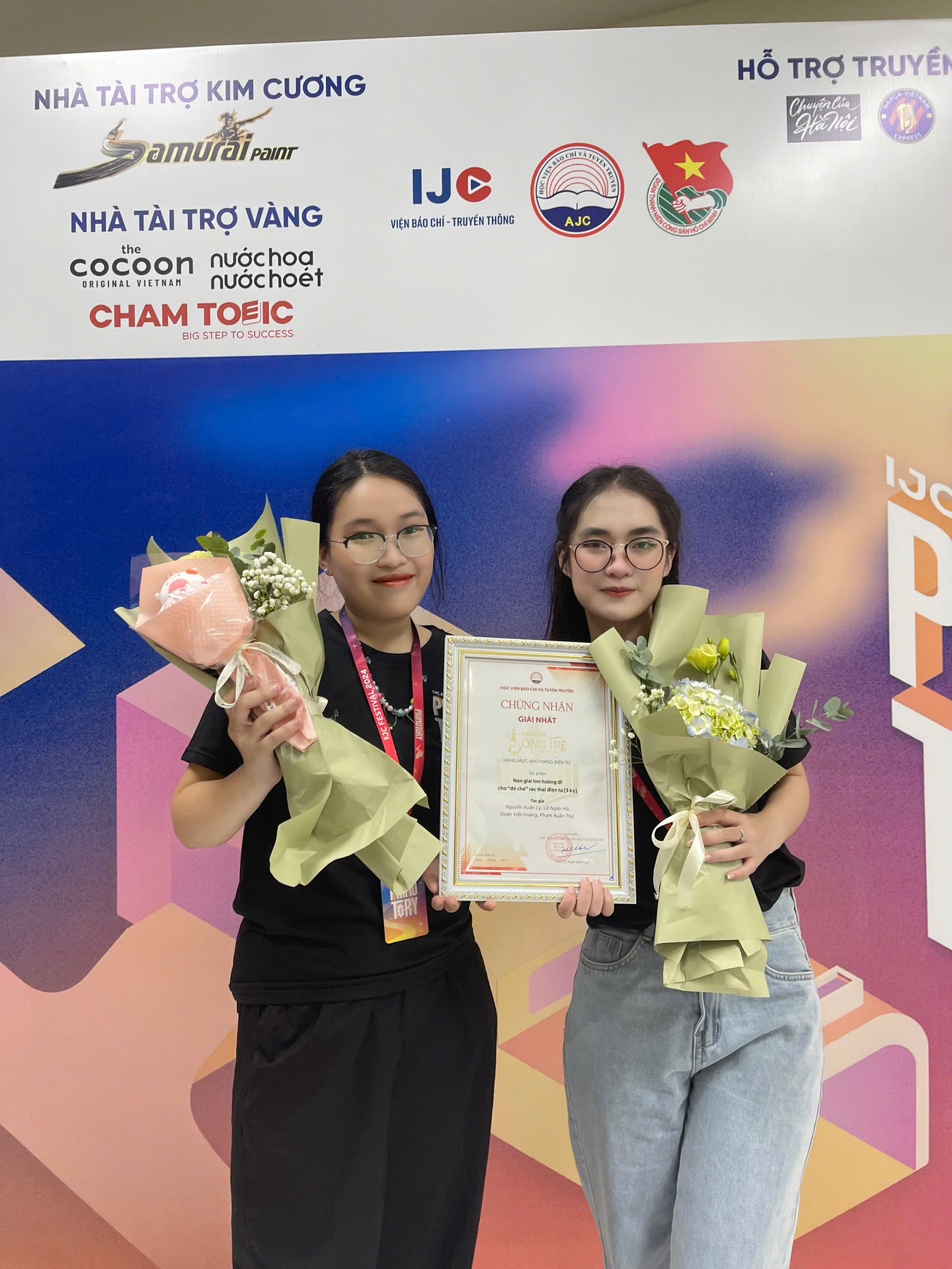 Hai thành viên nhóm tác giả – đại diện cho thế hệ sinh viên làm báo bằng sự tử tế và đam mê – chia sẻ khoảnh khắc nhận chứng nhận giải Nhất Giải Báo chí Sóng trẻ 2024 với nụ cười rạng rỡ và bó hoa chúc mừng.