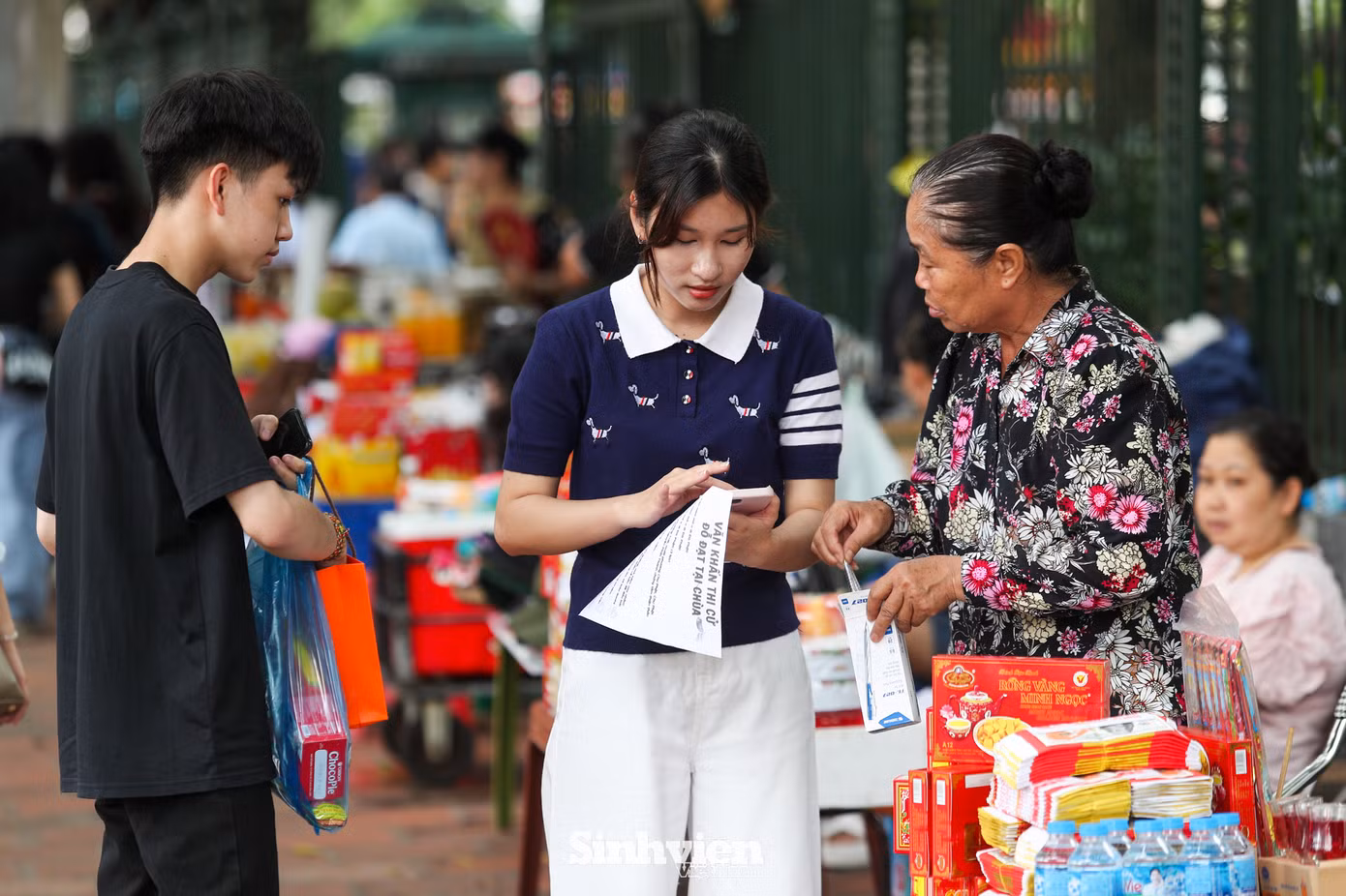 Khu vực ngoài cổng Văn Miếu nhộn nhịp mua bán lễ vật, một mâm lễ gồm tiền vàng mã, thẻ hương, bánh kẹo... kèm các đồ dùng thi cử như bút, tẩy có giá dao động từ 100.000 đến 200.000 đồng. Các sĩ tử được tặng kèm một bài văn khấn theo mẫu trên...facebook.