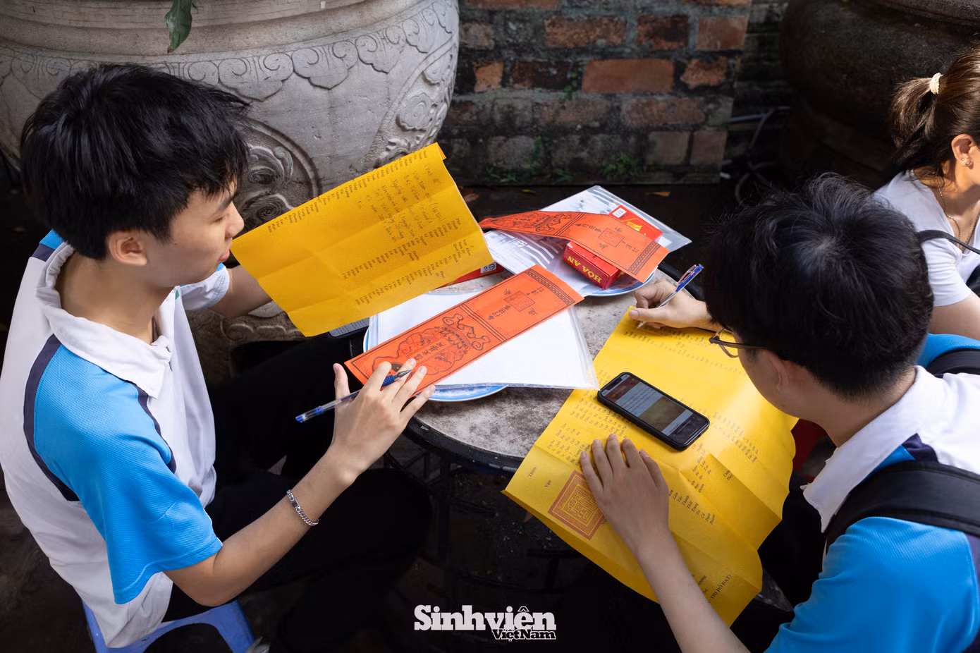 Cùng nhau đến dâng sớ, đôi bạn thân Minh Trí và Minh Tuệ có chung nguyện vọng vào khối ngành khoa học công nghệ. Minh Trí (bên trái) thật thà chia sẻ: "Mục tiêu của em là đỗ vào các trường top đầu như Bách Khoa, PTIT hay USTH. Càng gần ngày thi, chúng em càng hồi hộp nhưng cũng rất mong chờ. Hai đứa tự rủ nhau đến đây, rồi lên mạng tìm hiểu cách viết sớ cho đúng". Trí cười và nói thêm: "Em hy vọng sự thành tâm và chuẩn bị này sẽ mang lại một kỳ thi may mắn và thành công".