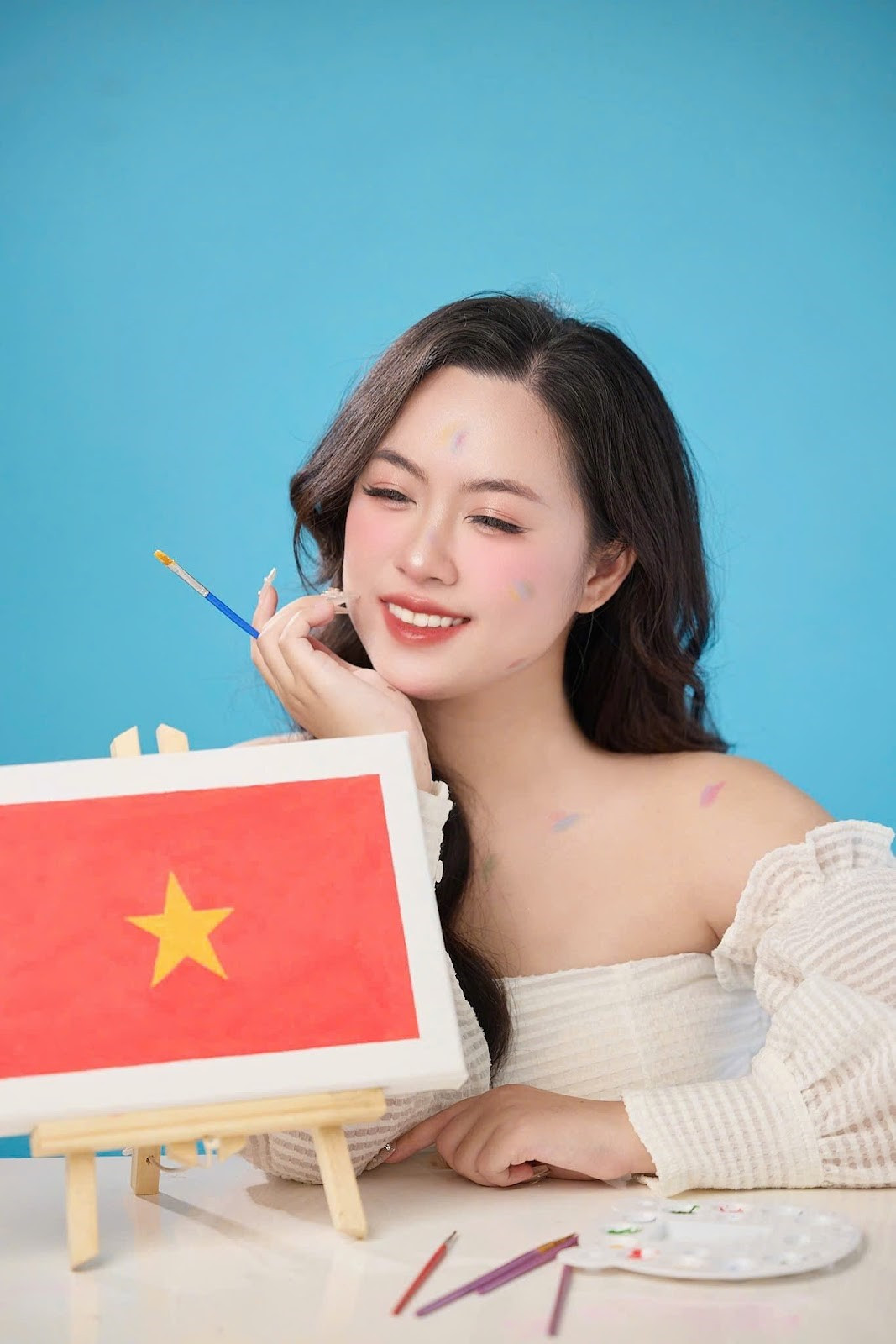 Nụ cười toả nắng của Hoa khôi Hồng Nhung bên bức tranh cờ Tổ quốc.